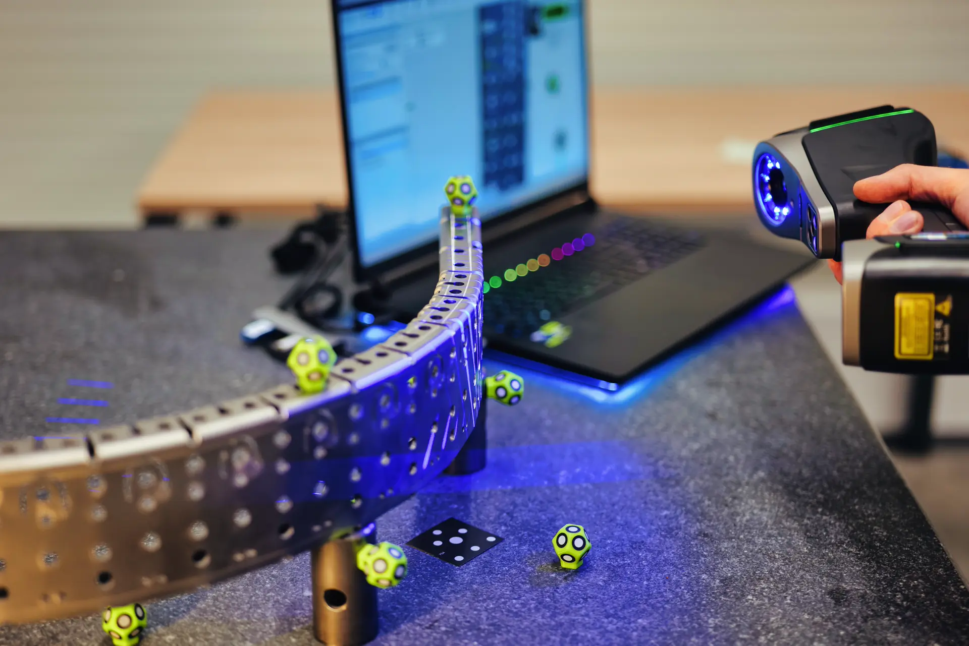 Kézi 3D-szkenner ívelt fémalkatrésznél a laptop mellett